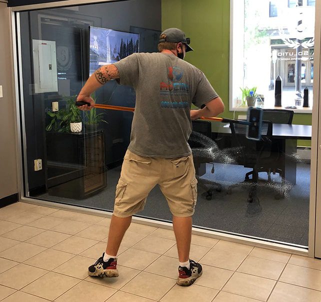 proelite worker cleaning a glass wall in office building