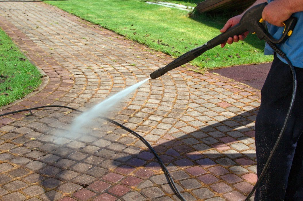 proelite worker pressure washing a brick sidewalk